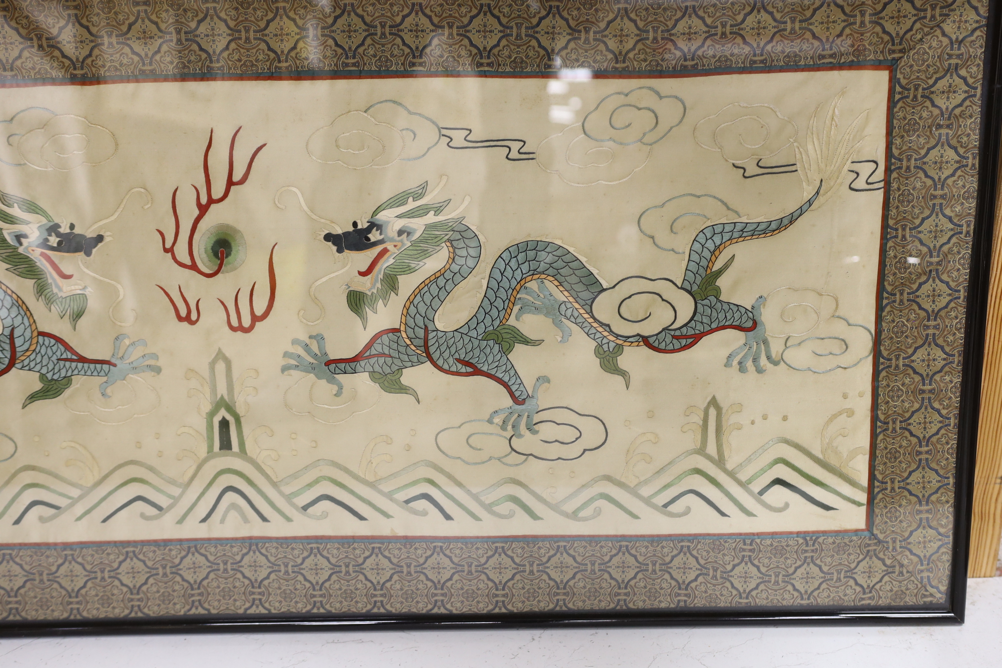 A framed 20th century Chinese silk embroidered 'dragon’ panel, with flaming pearl design, bordered with silk brocade